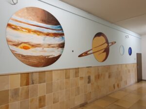 Das Bild zeigt gemalte Planeten an der Wand im Schulflur