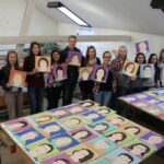 Unser Gebäude 40 Das Bild zeigt eine Gruppe von Schülerinnen und Schülern, die ihre gemalten Portraits präsentieren
