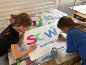 Das Bild zeigt Schülerinnen dabei, wie sie das Logo des Gymnasiums Wermelskirchen malen