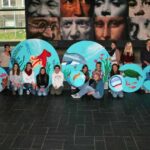 Unser Gebäude 54 Das Bild zeigt eine Gruppe Kinder, die ihre Bilder für die kreative Schulgestaltung zeigen
