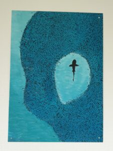 Das Bild zeigt ein gemaltes Bild von einem Hai in Mitten eines Fischschwarms