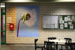 Das Bild zeigt eine gemalte Pusteblume im Schulflur hängend