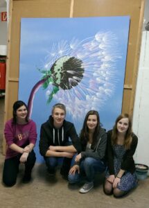 Das Bild zeigt Schülerinnen und Schüler, die vor ihrem gemalten Bild sitzen