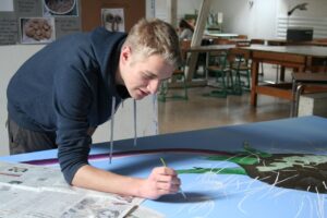 Das Bild zeigt einen Schüler beim Malen