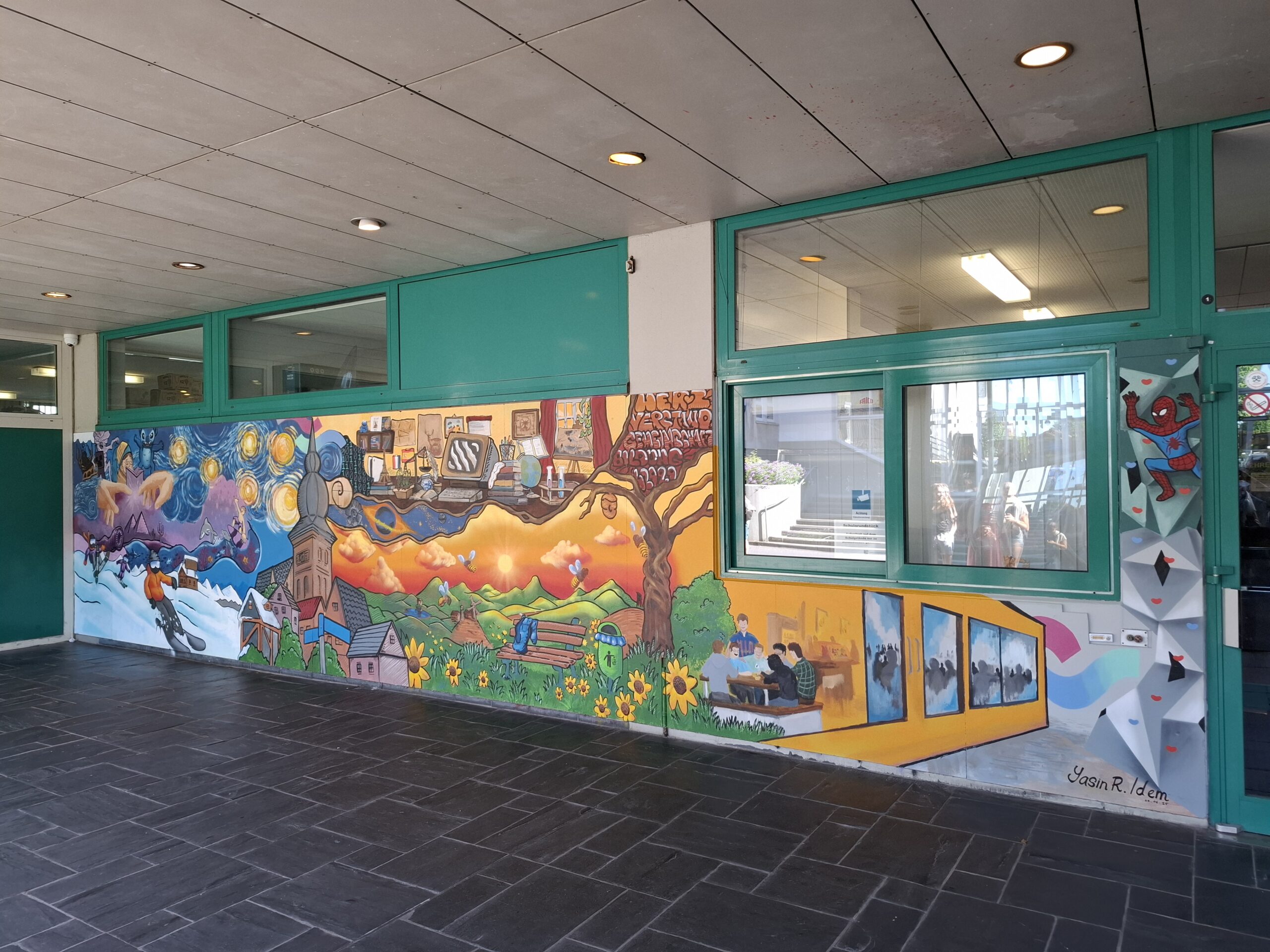 Das Bild zeigt eine bemalte Wand am Haupteingang der Schule